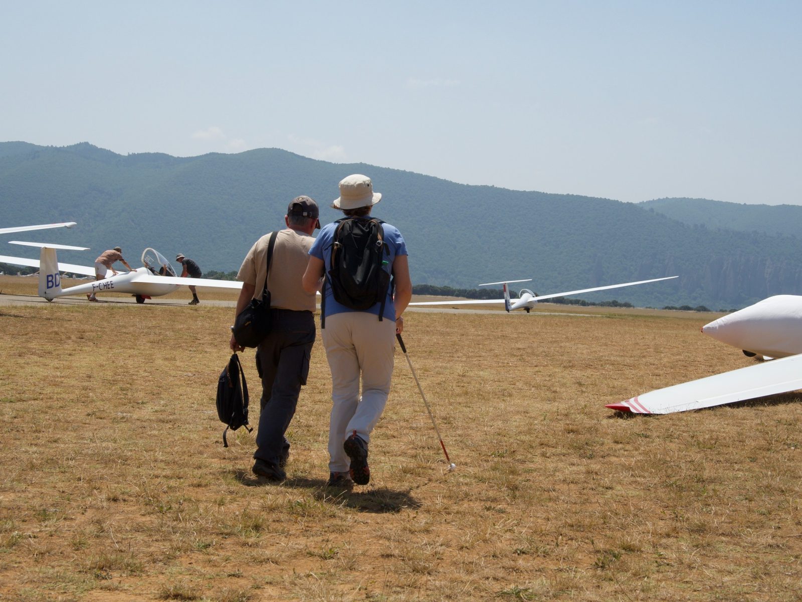 Valérie Mansard et Frédérick Vuaille se dirigent vers plusieurs planeurs stationnés au pied des montagnes.